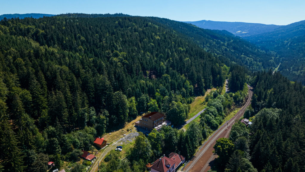 Údolí s domem, tratí a šumavskými lesy
